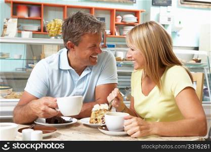Couple Enjoying Slice Of Cake And Coffee In Cafe