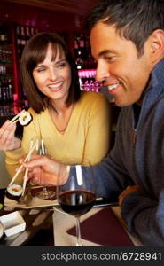 Couple Enjoying Sushi In Restaurant