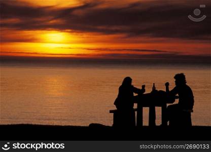 Couple enjoying wine and ocean sunset, Ecola State Park, Oregon
