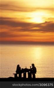 Couple enjoying wine and ocean sunset, Ecola State Park, Oregon