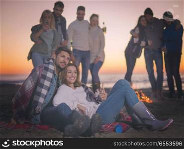 Couple enjoying with friends at sunset on the beach. Young Couple Sitting with friends Around Campfire on The Beach At sunset drinking beer colored filter