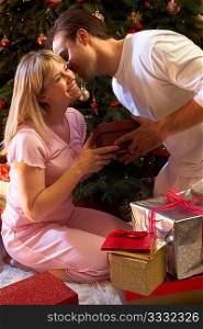 Couple Exchanging Presents In Front Of Tree