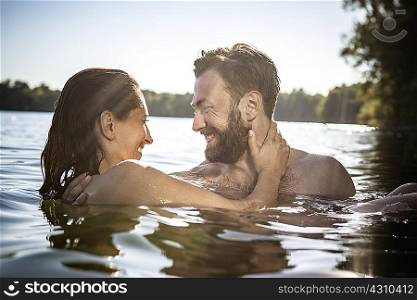 Couple face to face hugging, smiling in water, Berlin, Germany