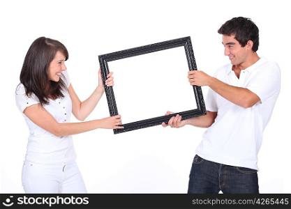 Couple fighting over blank picture frame