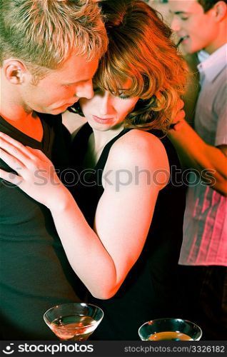 Couple flirting very obviously in a bar or at a club, cocktail drinks in front of them