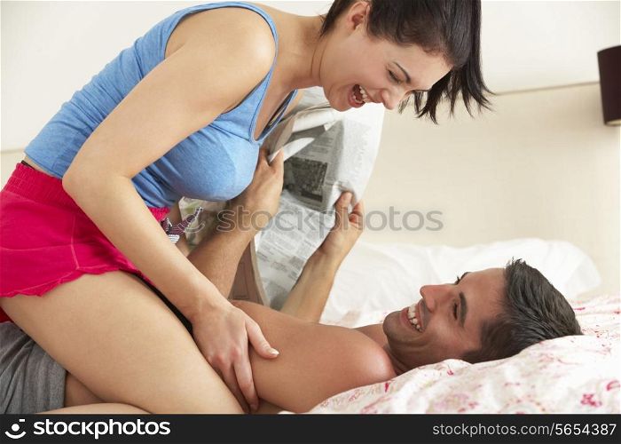 Couple Fooling Around Together In Bed Whilst Man Reads Newspaper