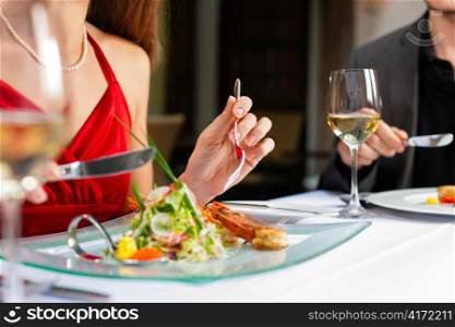 Couple for romantic Dinner or lunch in a gourmet restaurant drinking white wine and having great food