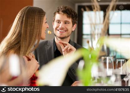 Couple for romantic Dinner or lunch in a gourmet restaurant, he is feeding her