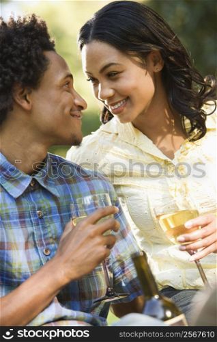 Couple getting close having wine on romantic park picnic.