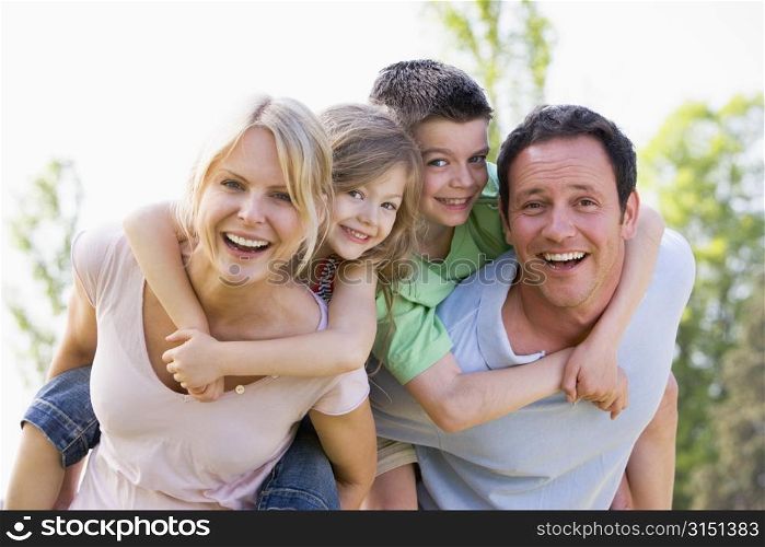 Couple giving two young children piggyback rides smiling