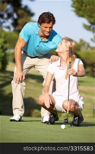 Couple Golfing On Golf Course Lining Up Putt On Green
