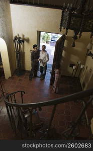 Couple greeting guest at door