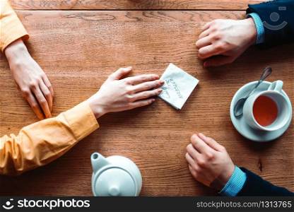 Couple hands with love note on wooden background top view. Man and woman romantic relationship