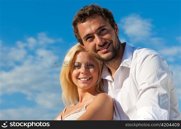 Couple having a city break in summer sitting on a brick wall in the sunlight