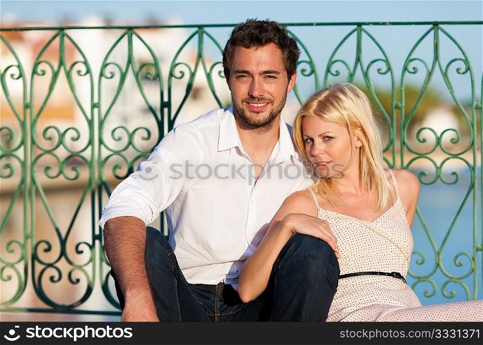 Couple having a city break in summer sitting on a bridge over a river in the evening light