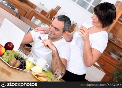 couple having breakfast and looking a computer
