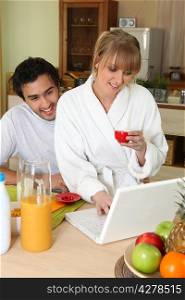 Couple having breakfast in front of laptop