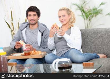 Couple having breakfast on couch