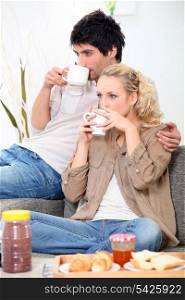 Couple having breakfast on the couch