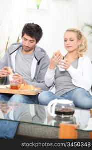 Couple having breakfast on the sofa