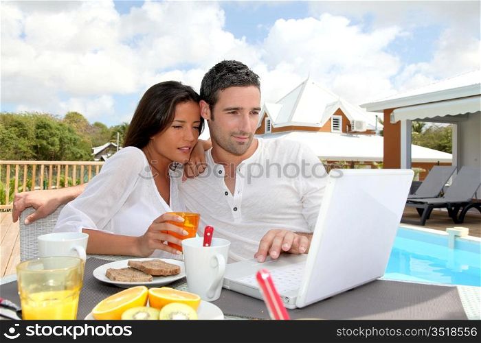 Couple having breakfast outside in front of laptop