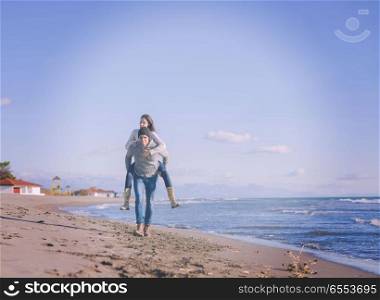 couple having fun at beach during autumn. Men Giving Piggy Back Rides At Sunset By The Sea, autumn time colored filter