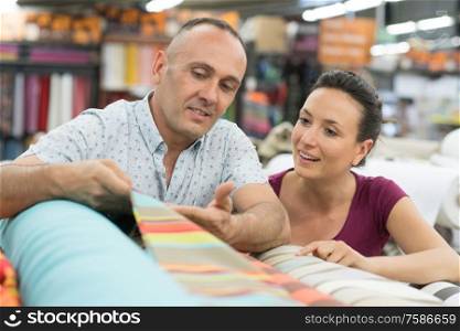 couple having fun in store choosing fabric
