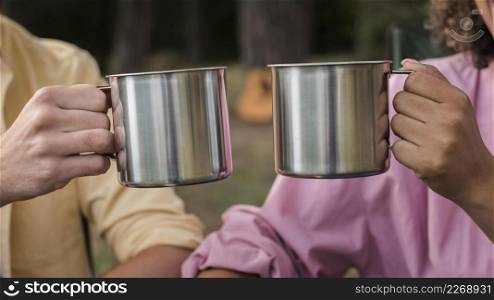 couple having hot drinks while camping outdoors