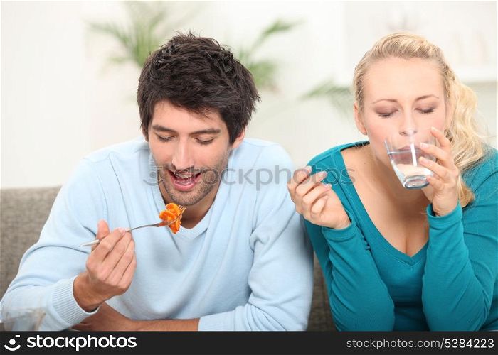 couple having lunch on a sofa