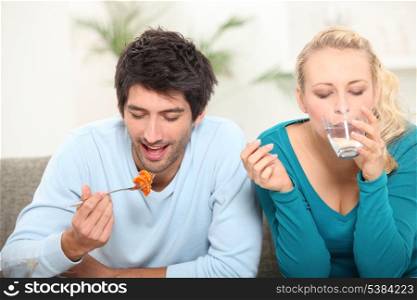couple having lunch on a sofa