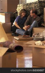Couple Having Pizza Dinner While Surrounded By Moving Boxes