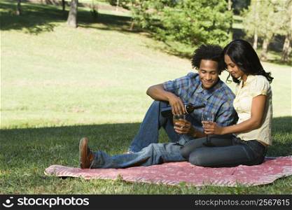Couple having romantic picnic in park drinking wine.