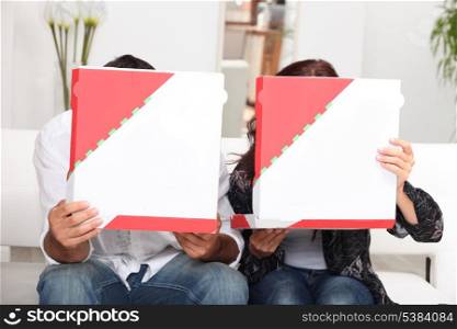 couple hiding behind pizza boxes