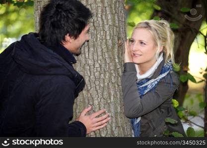 Couple hiding either side of tree