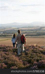Couple Hiking Across Moorland Covered With Heather