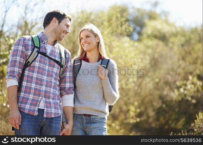 Couple Hiking In Countryside Wearing Backpacks