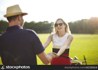 Couple holding hands and swirling each other around in park