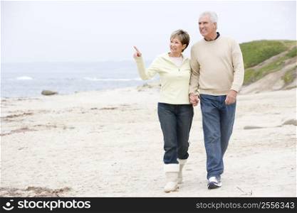 Couple holding hands at the beach smiling and pointing