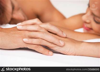Couple holding hands lying in bed focus on hands