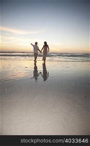 Couple holding hands on beach at sunset, Cape Town, South Africa