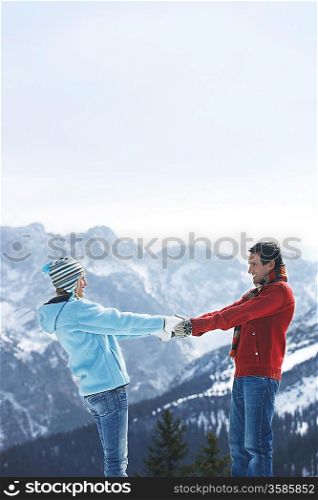 Couple holding hands standing face to face in mountains side view
