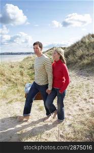 Couple holding hands walking on sand dune