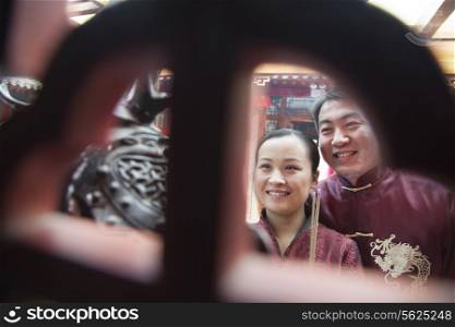 Couple holding offering incense at the temple in traditional clothing