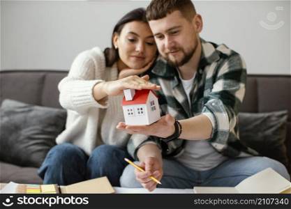 couple holding small house medium shot