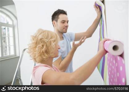 Couple holding up wallpaper samples in new house