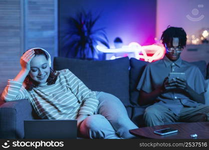 couple home together couch using modern devices