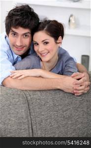 Couple hugging behind sofa