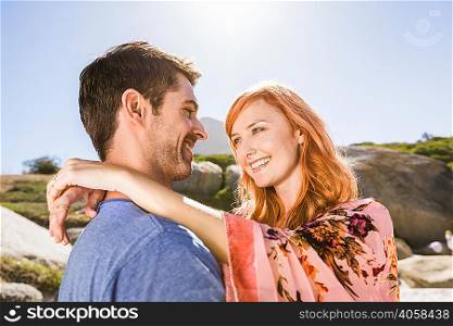 Couple hugging outdoors, face to face, smiling