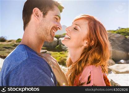 Couple hugging outdoors, face to face, smiling