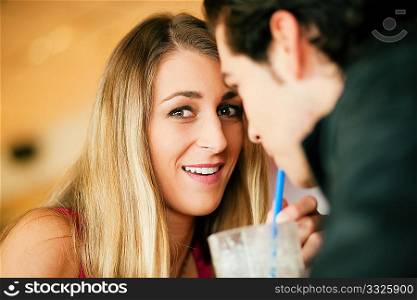Couple in a restaurant or diner, drinking a milkshake using a straw, shot with available light, very selective focus